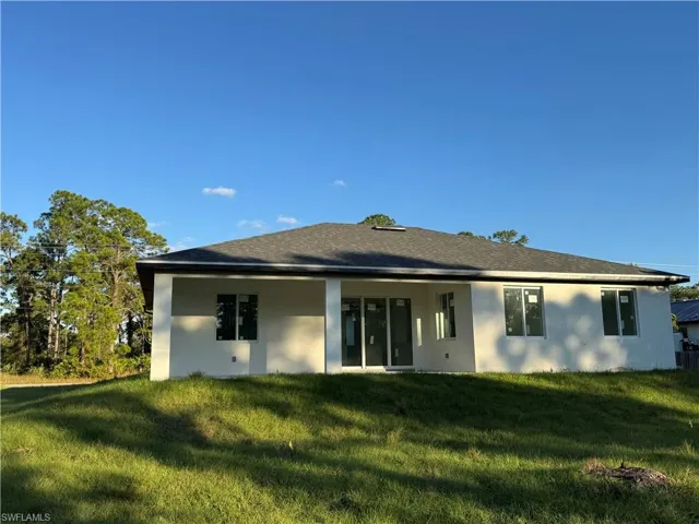 Rear view of property with stucco siding, a yard, and a patio