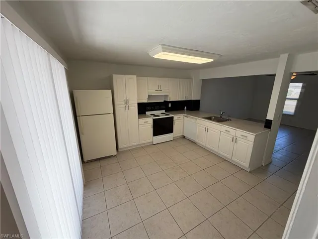 Kitchen featuring white cabinets, white appliances, light countertops, and light tile patterned floors