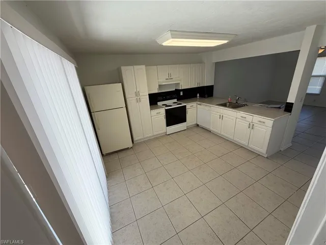 Kitchen featuring white cabinetry, white appliances, light countertops, and light tile patterned floors