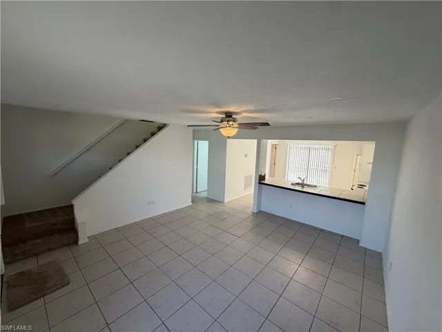 Unfurnished living room with light tile patterned floors and a ceiling fan