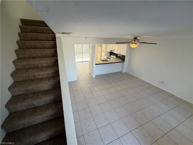 Stairs featuring tile patterned flooring and ceiling fan