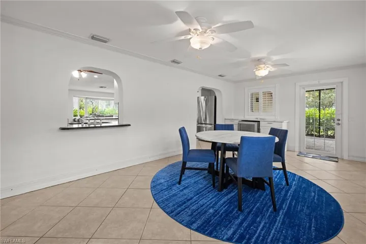 Dining area with arched walkways, light tile patterned floors, healthy amount of natural light, and beverage cooler