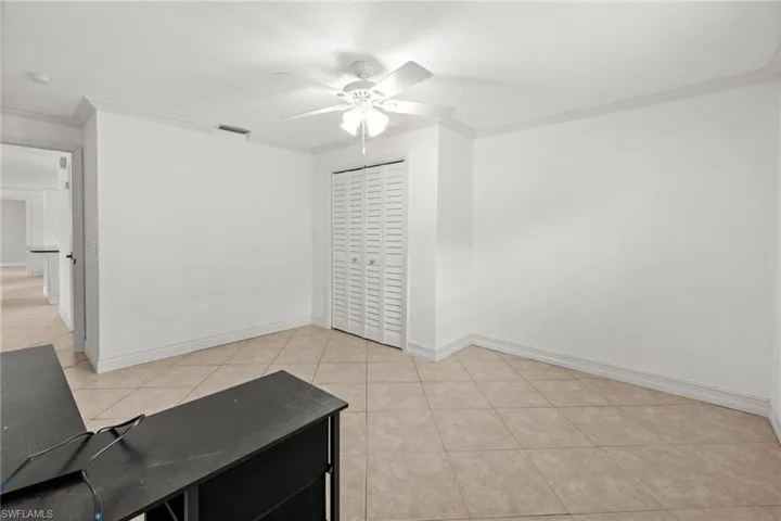 Spare room with ceiling fan, crown molding, light tile patterned flooring, and baseboards