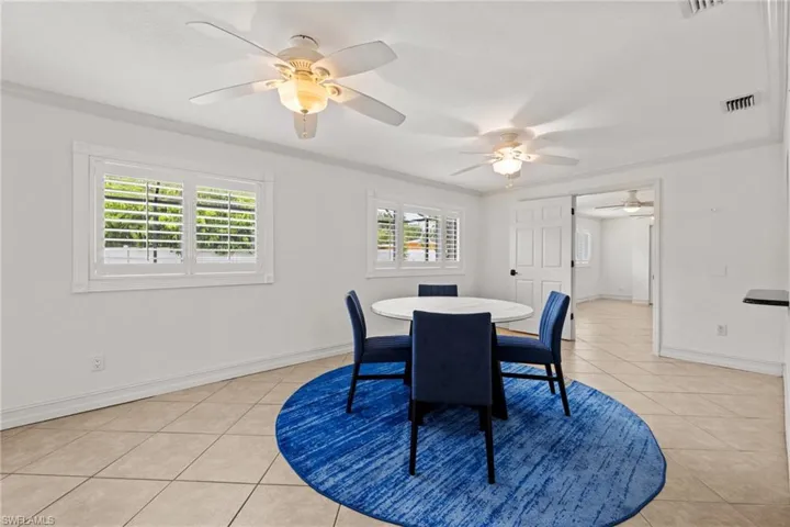 Dining space featuring a ceiling fan, light tile patterned floors, baseboards, and crown molding