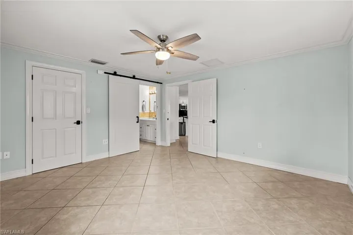 Unfurnished room featuring built in features, a ceiling fan, ornamental molding, arched walkways, and baseboards