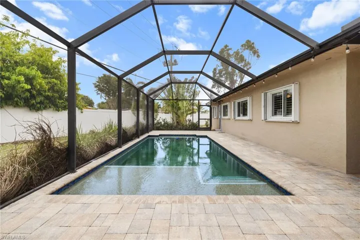 View of swimming pool featuring a lanai, a patio, and fence