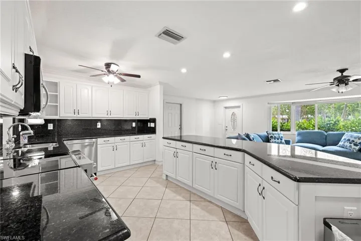 Kitchen with ceiling fan, open floor plan, a sink, white cabinets, and recessed lighting