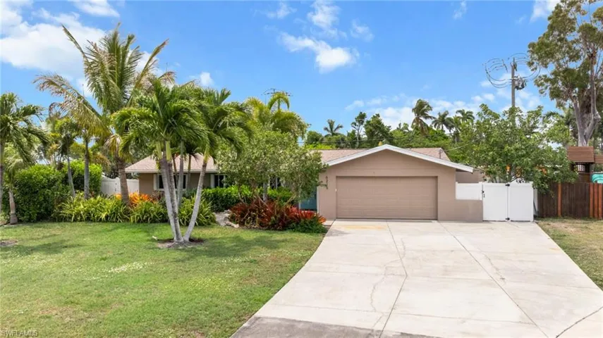 Obstructed view of property featuring stucco siding, a garage, driveway, and a gate