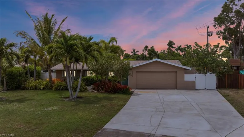View of front of house featuring a garage, concrete driveway, stucco siding, and a gate