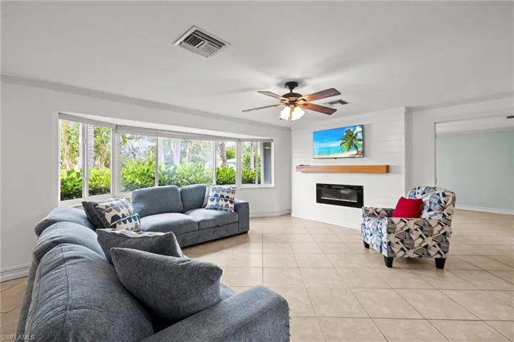 Living room with baseboards, a fireplace, light tile patterned flooring, and a ceiling fan