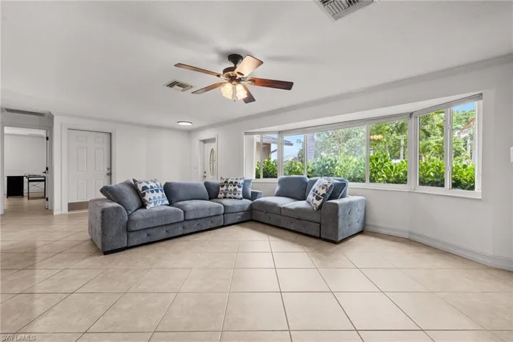 Living room with light tile patterned floors, ceiling fan, and baseboards
