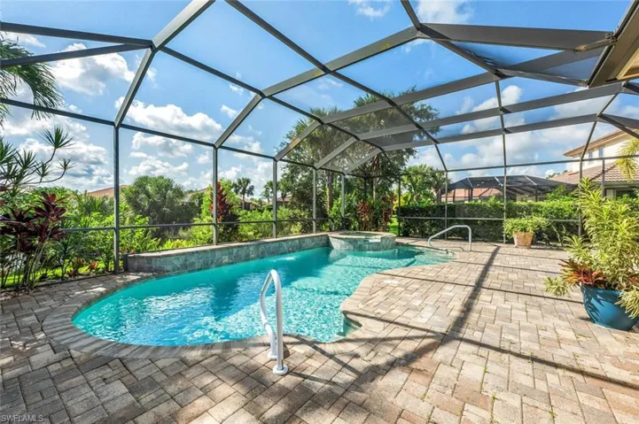View of swimming pool featuring an in ground hot tub, a patio, pool water feature, and a lanai