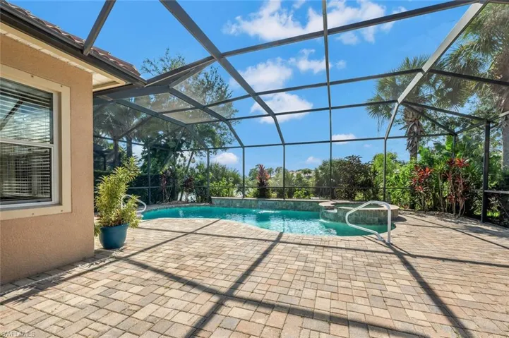 View of pool featuring an in ground hot tub, a lanai, pool water feature, and a patio area