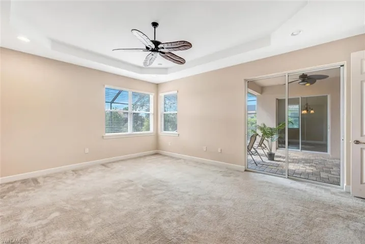 Spare room featuring carpet floors, a tray ceiling, and ceiling fan