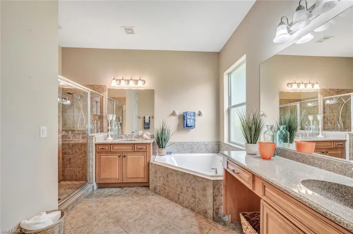 Bathroom featuring tile patterned flooring, separate shower and tub, and vanity