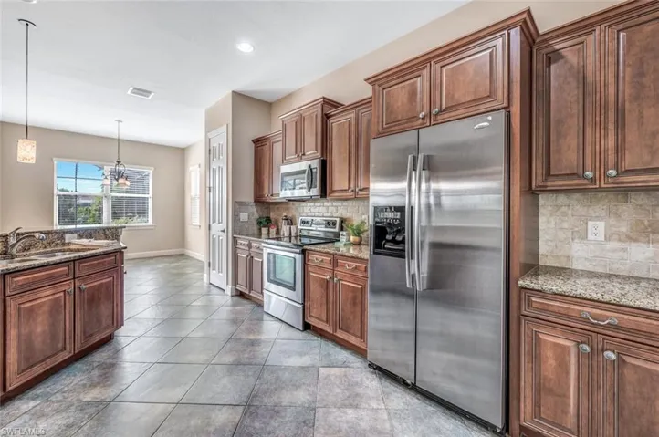 Kitchen with stainless steel appliances, tasteful backsplash, sink, and stone countertops