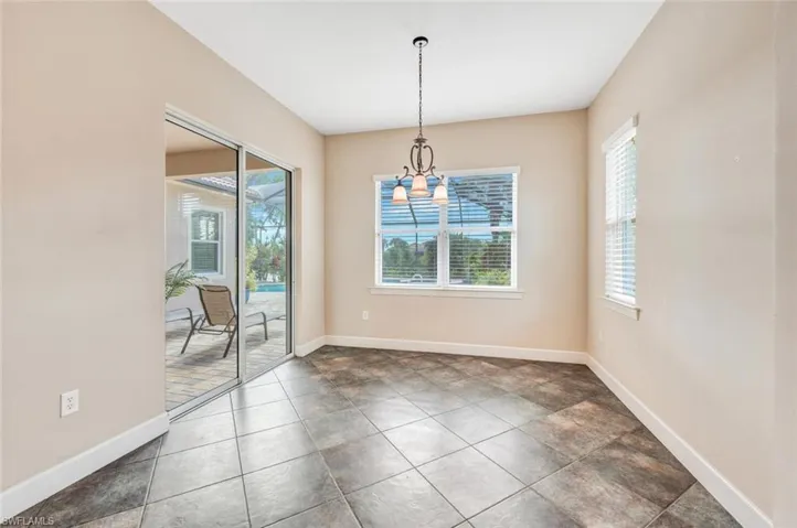 Unfurnished dining area with dark tile patterned floors and an inviting chandelier
