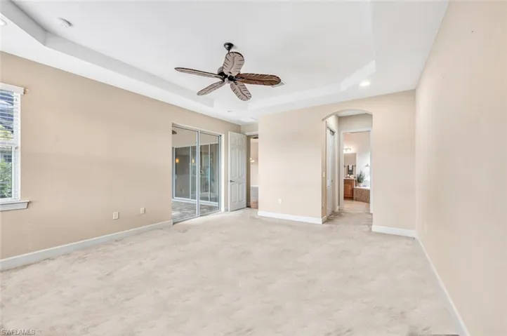 Spare room with ceiling fan, light carpet, and a tray ceiling