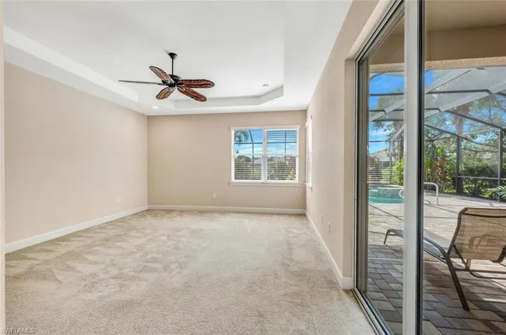 Spare room featuring a tray ceiling, light colored carpet, and ceiling fan