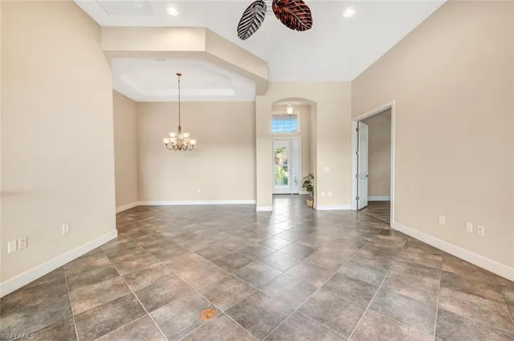 Spare room with a chandelier, a tray ceiling, and dark tile patterned flooring