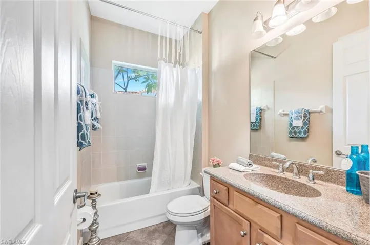 Full bathroom with vanity, shower / bath combo with shower curtain, tile patterned flooring, and toilet