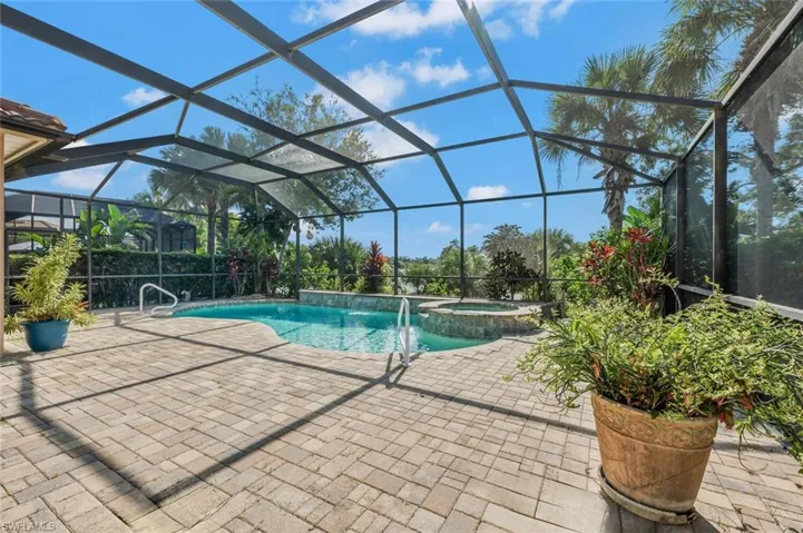 View of pool featuring a patio, an in ground hot tub, pool water feature, and a lanai
