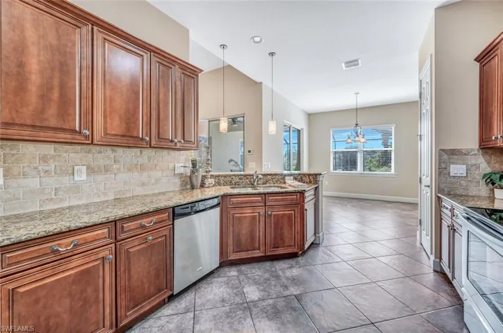 Kitchen featuring stainless steel appliances, sink, decorative light fixtures, light tile patterned floors, and decorative backsplash