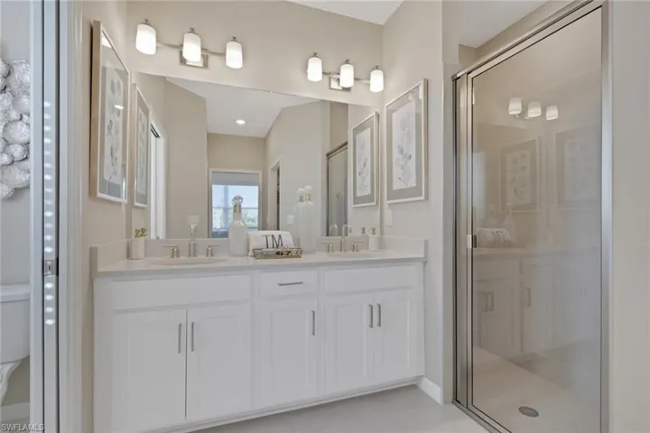 Bathroom with a shower stall, double vanity, and light tile patterned floors