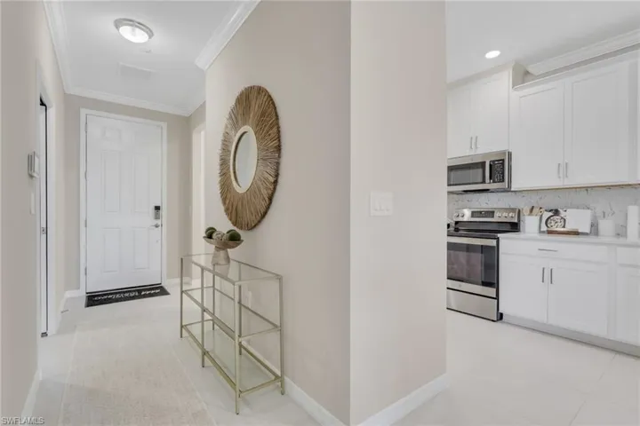 Corridor with crown molding and light tile patterned floors