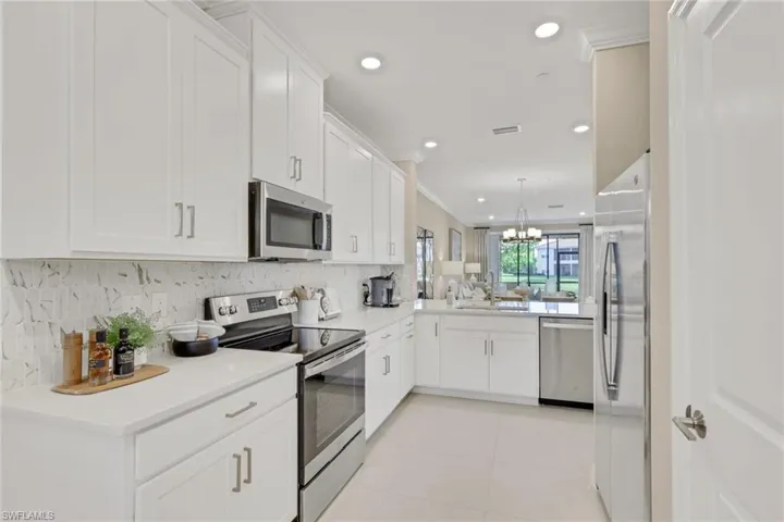 Kitchen with appliances with stainless steel finishes, white cabinets, hanging light fixtures, recessed lighting, and backsplash