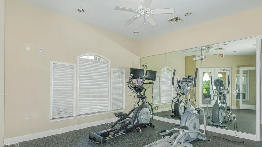 Community workout area with healthy amount of natural light, ceiling fan, and rubber floors