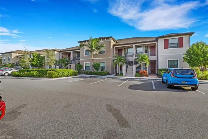 View of property with stairs and uncovered parking