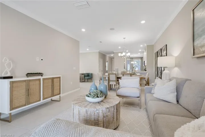 Tiled living room with ornamental molding, recessed lighting, and a chandelier