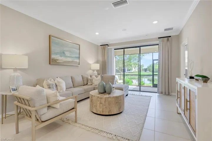 Living room featuring ornamental molding, light tile patterned floors, a water view, and recessed lighting