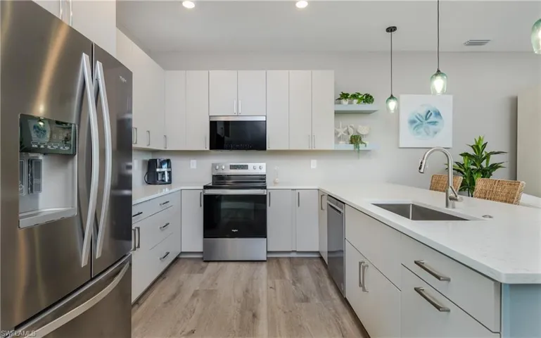 2nd-level kitchen: stainless steel appliances, white cabinetry, an island with an under-mount sink, and recessed lighting
