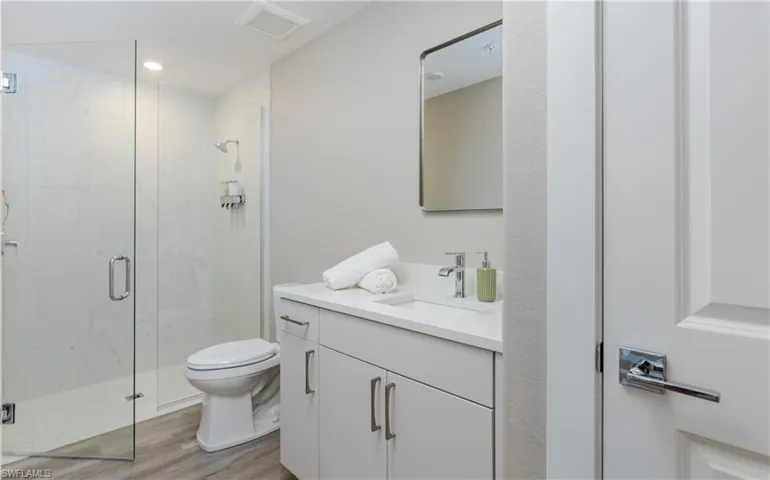 Quest suite 1st level full-bathroom-Glass-enclosed shower, single vanity with integrated sink, and a contemporary wall mirror.