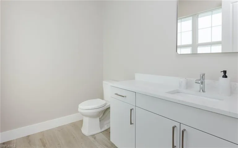 On the 2nd-level, guest half-bath, white vanity with integrated sink, chrome faucet, rectangular frameless mirror.
