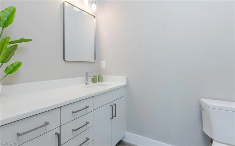 White countertop with an integrated sink, vanity with ample storage, and a framed rectangular mirror