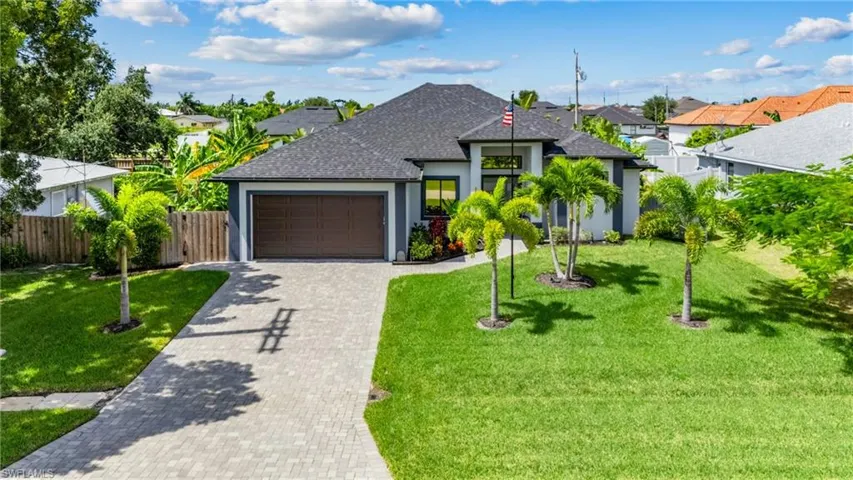 View of front of home featuring stucco siding, a front lawn, a shingled roof, decorative driveway, and a garage