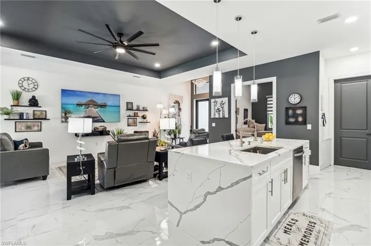 Kitchen featuring open floor plan, a raised ceiling, a sink, visible vents, and light stone countertops