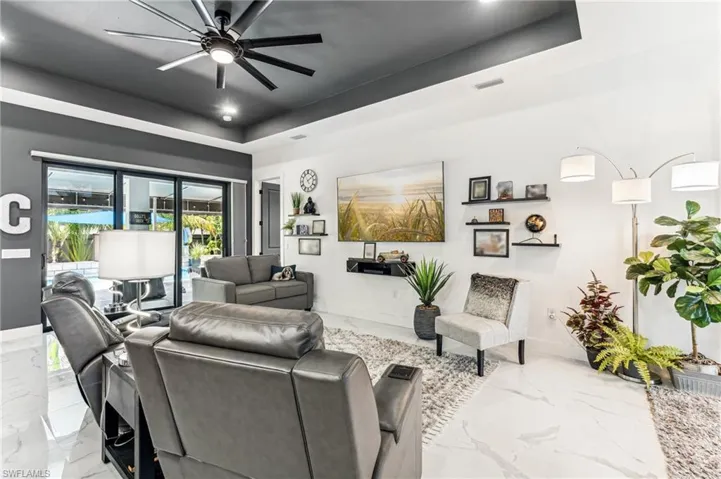 Living room with visible vents, baseboards, marble finish floor, a ceiling fan, and a tray ceiling