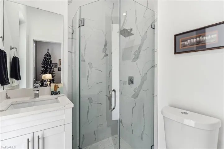Bathroom featuring toilet, vanity, and a marble finish shower