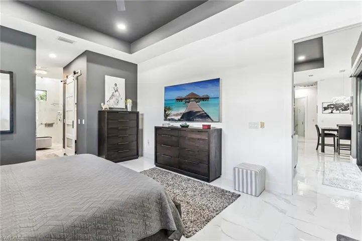 Bedroom featuring visible vents, baseboards, marble finish floor, recessed lighting, and a barn door
