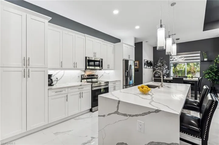 Kitchen with marble finish floor, light stone countertops, stainless steel appliances, tasteful backsplash, and a sink