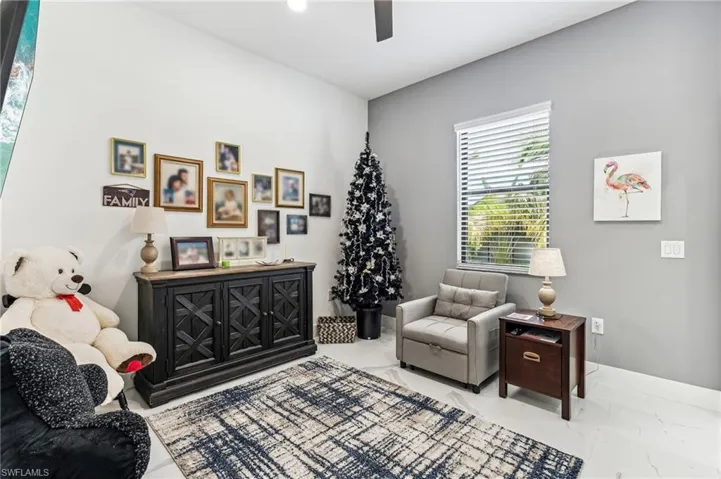Living area featuring baseboards, marble finish floor, and ceiling fan
