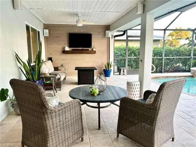 View of patio / terrace featuring glass enclosure, a sunroom, ceiling fan, an outdoor pool, and outdoor furniture