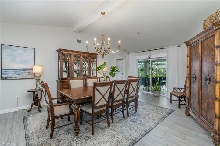 Dining space with a notable chandelier, lofted ceiling  and plank style flooring