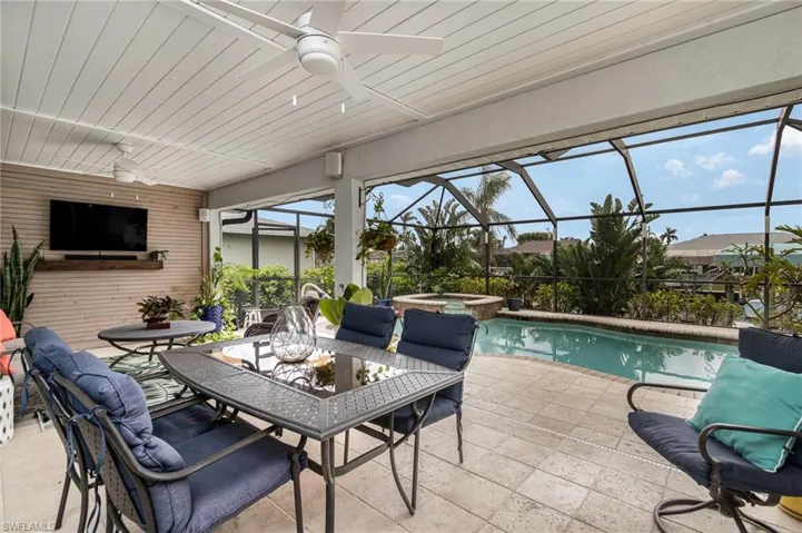 View of swimming pool featuring a spa, ceiling fan, a patio area, and a lanai