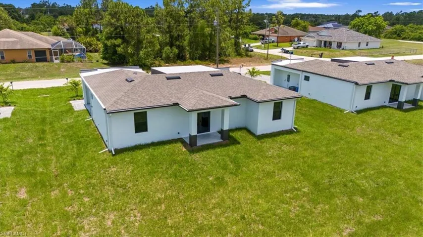 Back of property with a yard, a patio, and roof with shingles
