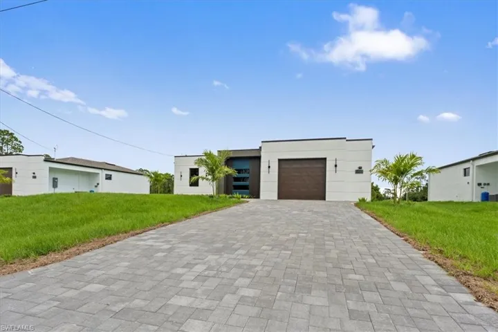 Modern home featuring a front lawn, decorative driveway, a garage, and stucco siding